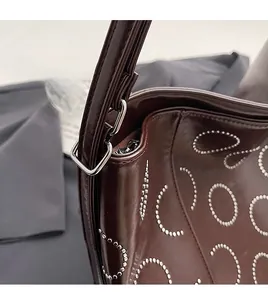 Detailed close-up of dark wine red leather bag with silver rivets and polished hardware