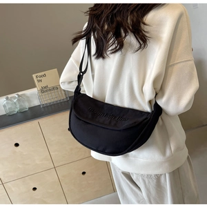 Close-up of black crescent nylon crossbody bag with mountain line text on a model