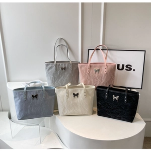 Detail view of five textured tote bags with metallic butterfly buckles in various colors