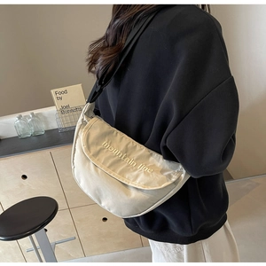 Close-up of beige moon-shaped canvas bag with mountain line embroidery and black strap