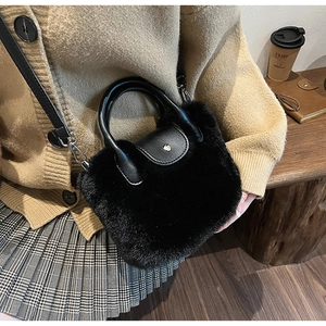 Détail d'un sac à main en peluche noire avec anses en cuir et bandoulière amovible