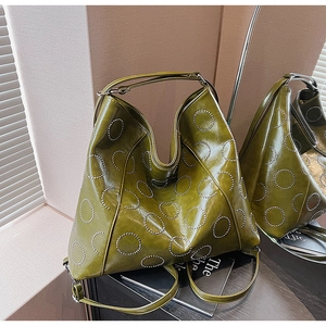 Detail of olive green tote bag with silver metal studs and polished synthetic leather