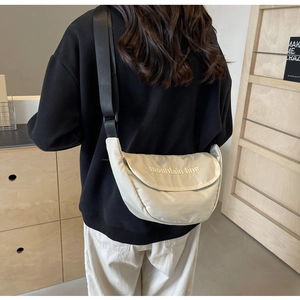 Detail of off-white nylon half-moon bag featuring mountain line embroidery and wide strap
