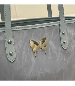 Macro detail of silver butterfly ornament on marble textured light blue tote bag