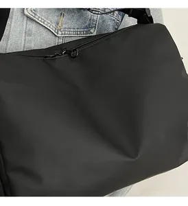 Gros plan d'un sac bandoulière en nylon noir léger avec broderie et sangle réglable