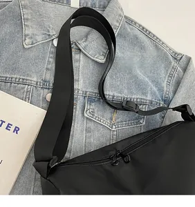 Détail de la bandoulière réglable et des poches zippées sur un sac cabas en nylon noir