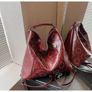 Macro shot of deep red leather bag featuring polished metallic rivet circular patterns