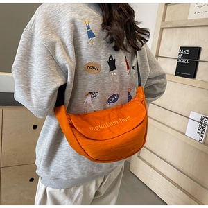 Detail of orange canvas crescent bag with mountain line embroidery and black strap