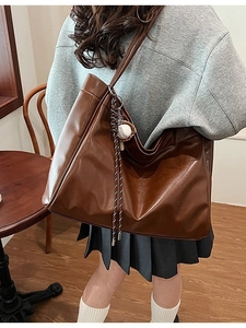 Brown faux leather tote bag with baseball charm shown in a cozy cafe setting