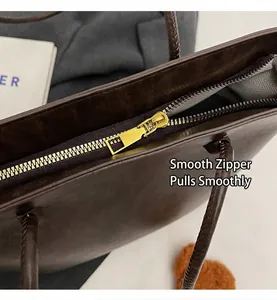 Nahaufnahme des glatten goldfarbenen Reißverschlusses an einer braunen Lederhandtasche