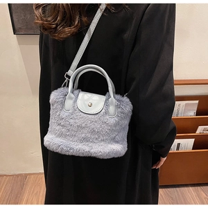 Détail d'un sac à main bleu clair en fausse fourrure avec poignée en cuir et rivets