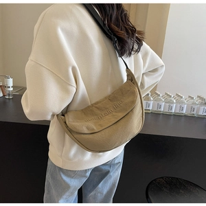 Detail of khaki crescent crossbody bag with embroidered mountain line text on a model