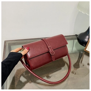 Dettaglio di una borsa a tracolla vintage in pelle bordeaux su un tavolo di vetro