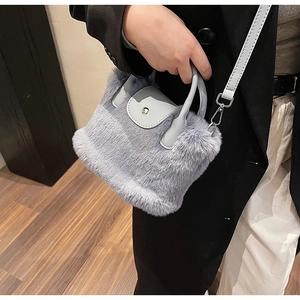 Détail de la texture pelucheuse et de la poignée en cuir du mini sac à bandoulière bleu