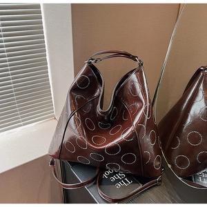 Macro view of dark brown faux leather hobo bag with silver stud circular pattern