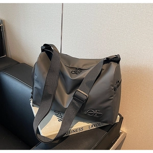 Détail d'un sac bandoulière noir imperméable avec logo en métal sur un canapé en cuir