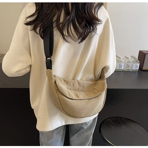 Detail view of khaki moon-shaped canvas bag featuring mountain line embroidery and strap