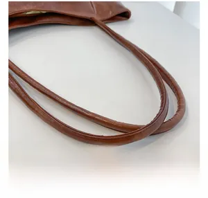 Dettaglio dei doppi manici e delle cuciture di una borsa tote in ecopelle marrone
