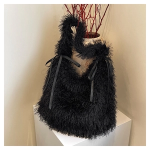 Detail of black faux fur tote bag featuring a decorative satin bow on a white pedestal