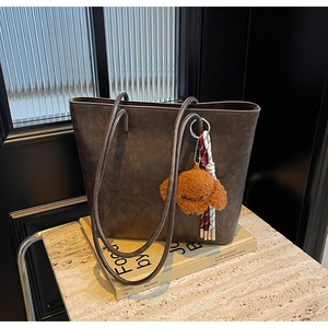 Dettaglio della borsa tote vintage marrone con ciondolo a forma di cane in peluche