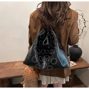 Detail of black faux leather tote with silver stud circles shown in a lifestyle shot