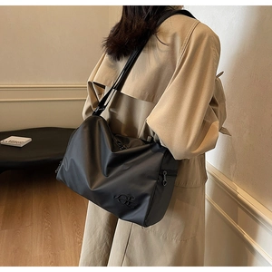 Vue détaillée du sac bandoulière en nylon noir avec sangle réglable et logo sur un mannequin