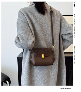 Detail view of brown leather and suede crossbody bag featuring a golden oval metal lock