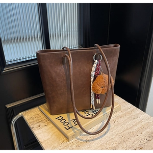 Dettaglio borsa shopper in pelle marrone con ciondolo a forma di cane su marmo