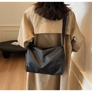 Détail du sac bandoulière noir avec logo OT brodé et large sangle réglable
