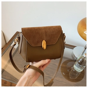 Close-up of brown crossbody bag featuring mixed textures and a gold metal buckle