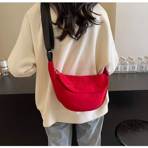 Detail of red crescent canvas bag featuring mountain line embroidery and adjustable strap