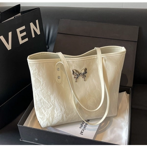 Detail of silver butterfly ornament on cream tote bag with elegant marble texture