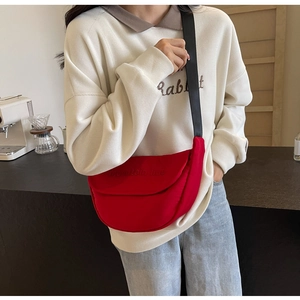 Close-up of red canvas crossbody bag with Mountain Line text worn by model