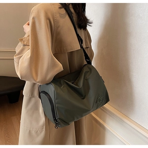 Détail d'un sac d'épaule en nylon vert foncé avec broderie OE et poche zippée latérale