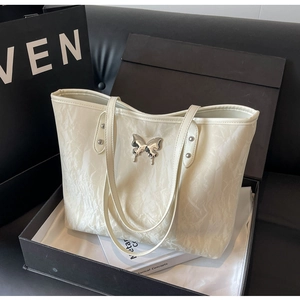 Detailed macro shot of an ivory tote bag with crinkle texture and silver butterfly buckle