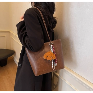 Dettaglio della borsa tote vintage in pelle marrone con ciondolo a testa di cane