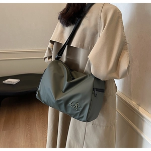 Détail du sac bandoulière en nylon vert olive avec logo OI en métal et fermeture éclair