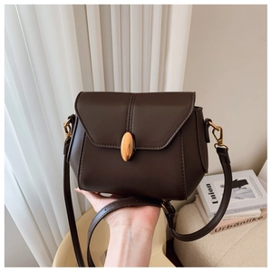 Detailed close-up of dark brown vintage flap bag with gold oval buckle and matte texture