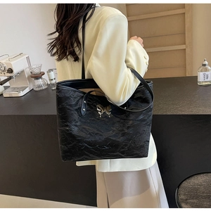 Detail of black tote bag with silver butterfly buckle and pleated texture material