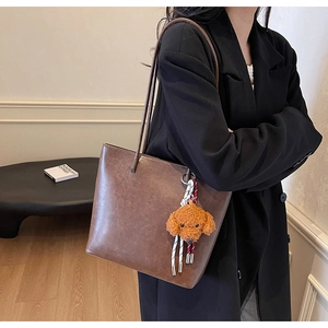 Dettaglio della borsa tote in pelle opaca marrone con un simpatico ciondolo a cucciolo
