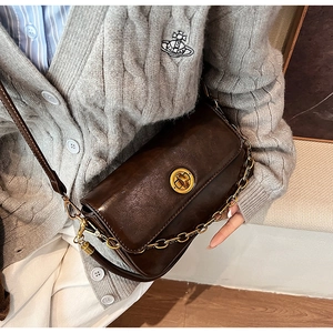 Detail of vintage chocolate brown glossy leather bag with golden circular twist lock