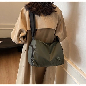 Détail du sac à bandoulière en nylon vert foncé avec sangle réglable sur le modèle