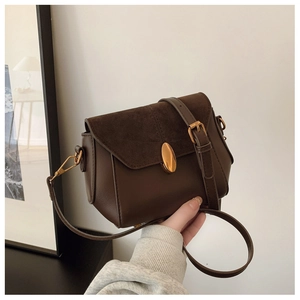 Detail of vintage coffee crossbody bag featuring smooth leather and suede texture with gold buckle