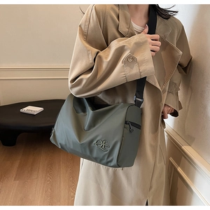 Détail du sac en nylon vert olive montrant le tissu imperméable et le logo en métal