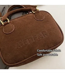 Detalle de ante marrón suave y logotipo grabado en un bolso de mano cuadrado vintage