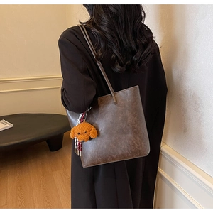 Dettaglio della borsa tote vintage marrone scuro con ciondolo a forma di orsetto di peluche