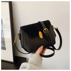 Detail of vintage black crossbody bag with gold oval lock and textured suede flap