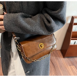 Close-up of a brown vintage leather handbag with a gold twist lock and metal chain