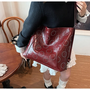 Close-up of burgundy tote bag with silver dot patterns and adjustable shoulder strap