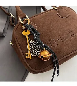 Detalle de bolso de ante marrón con relieve KEDEAR y colgantes metálicos decorativos
